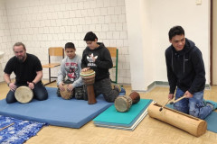 Žáci a lektor hrají na bubny.