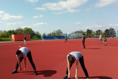 Žáci se rozcvičují na atletickém stadionu.