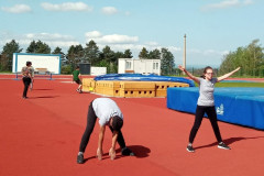 Žáci se rozcvičují na atletickém stadionu.