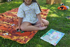 Dívka skládá puzzle venku na dece.