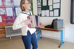 Paní učitelka hraje na tahací harmoniku.
