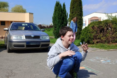 Chlapec maluje křídou na chodník.