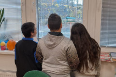 Žáci z okna pozorují krmítko.