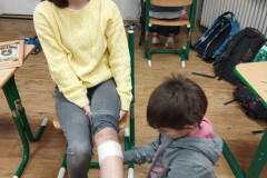 Dívka zkouší na druhé ovázání kolene.