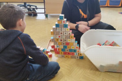 Chlapec skládá pyramidu s paní asistentkou.
