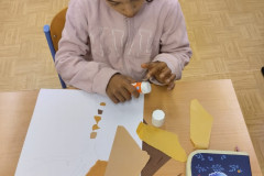 Chlapec  lepí kousky barevných papírů.