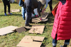 Žáci dávají karton pod štěpku okolo keřů.