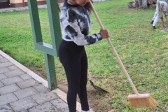 Dívka zametá chodník.