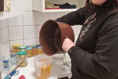 Dívka přelévá z hrnce do plastové nádoby.