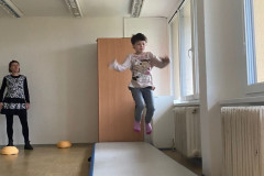 Dívka skáče na gymnastickém koberci.