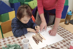 Chlapec natírá dřevěné špachtle na hnědo.