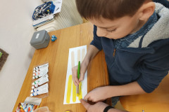 Chlapec natírá dřevěné špachtle na žluto.