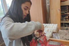 Dívka vyrábí robota ze dřeva a šroubků.