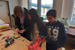 Žáci vyrábí robota ze dřeva a šroubků.
