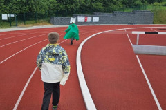 Žáci běží na atletickém oválu.
