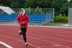 Chlapec běží na atletickém oválu.