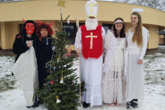 Mikuláš, čerti a andělé u vánočního stromečku.