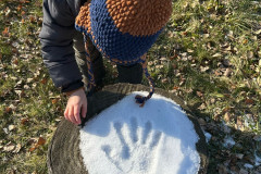 Dívka a otisk ruky ve sněhu.