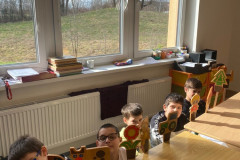 Žáci za stolem s dřevěnými obrázky.