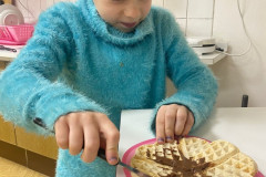 Dívka maže nutelu na wafle.