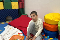 Chlapec si hraje na koberci s legem.